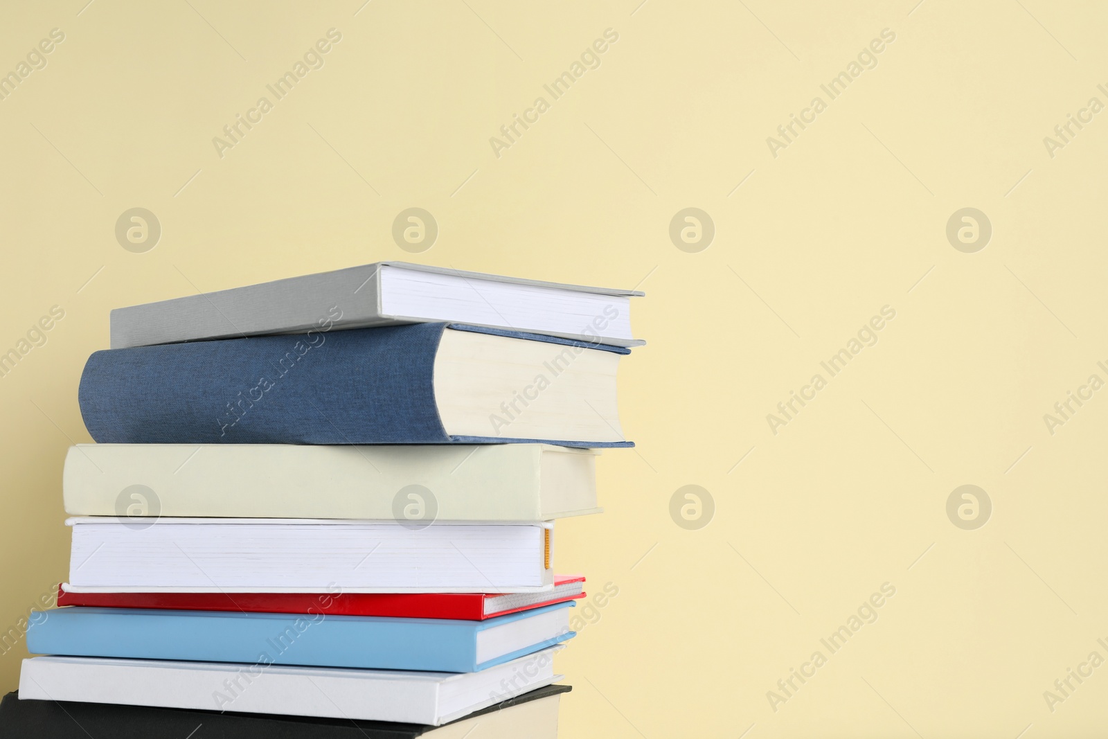 Photo of Stack of different books on beige background, space for text