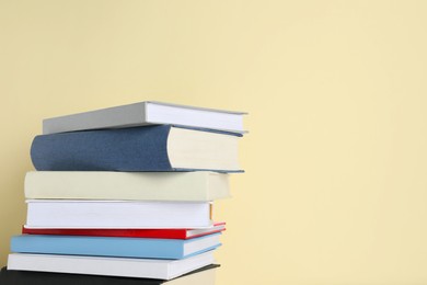 Stack of different books on beige background, space for text