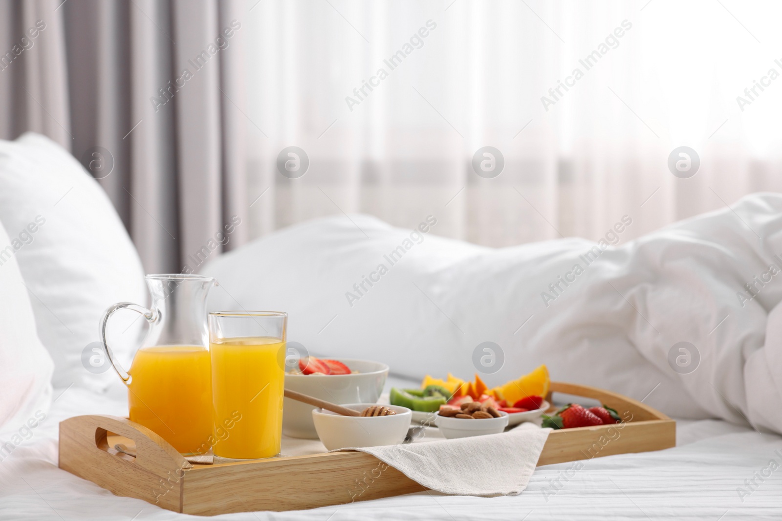 Wooden tray with tasty breakfast on bed at home Photo of Wooden tray with tasty breakfast on bed at home