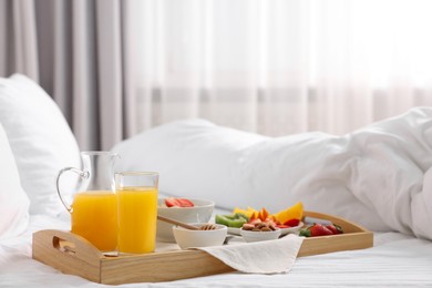 Photo of Wooden tray with tasty breakfast on bed at home
