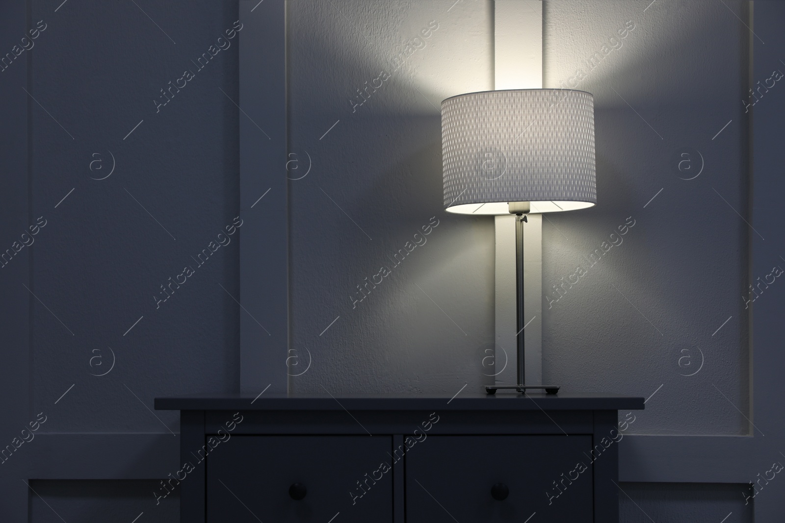 Photo of Wooden chest of drawers with lamp near wall in room, space for text