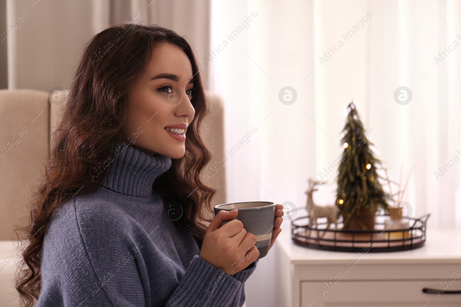 Photo of Woman with cup of hot drink resting at home. Winter atmosphere