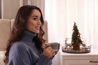 Photo of Woman with cup of hot drink resting at home. Winter atmosphere