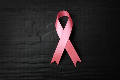 Pink ribbon on wooden background, top view. Breast cancer concept