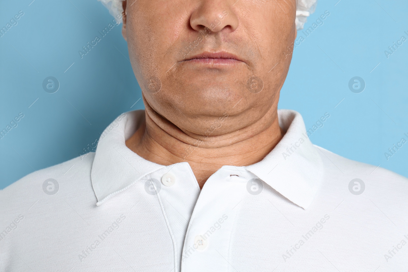 Photo of Mature man with double chin on blue background, closeup