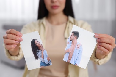 Photo of Woman holding torn photo at home, closeup. Divorce concept