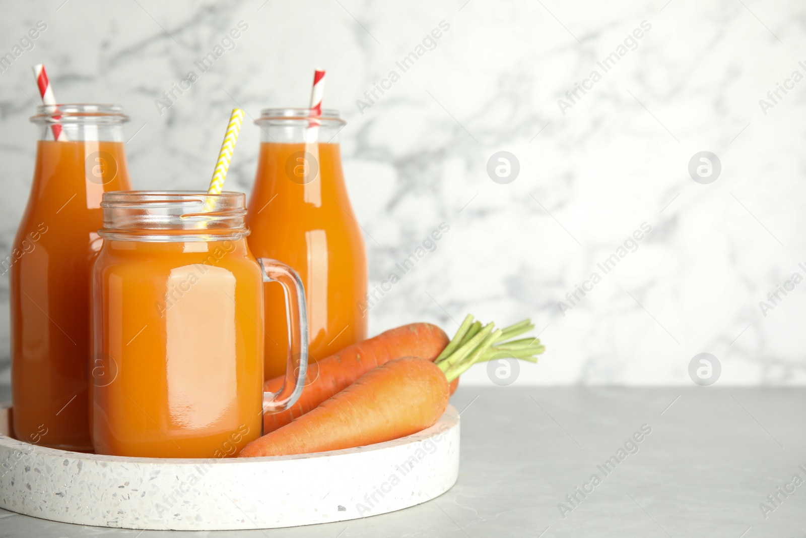 Photo of Freshly made carrot juice on white table, space for text