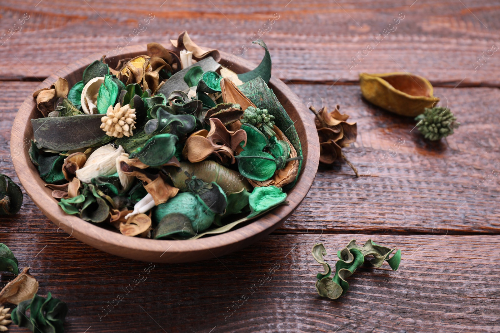 Photo of Aromatic potpourri of dried flowers in bowl on wooden table. Space for text