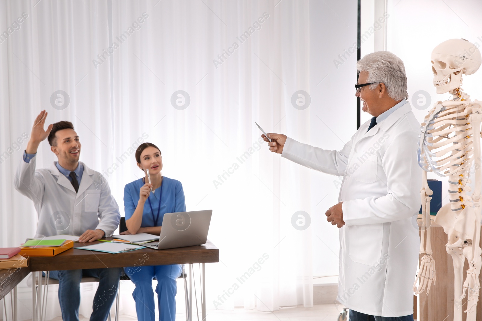 Photo of Medical students and professor studying human skeleton anatomy in classroom