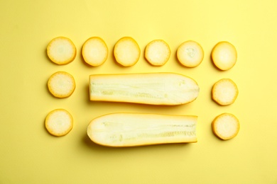 Fresh ripe cut zucchinis on yellow background, flat lay