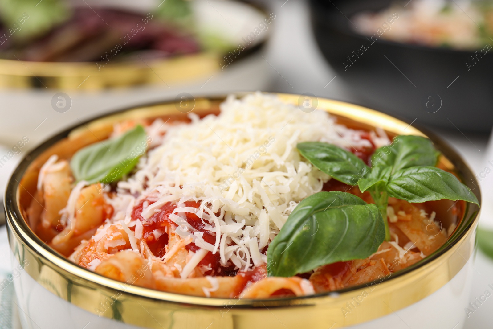 Photo of Delicious pasta with tomato sauce, basil and parmesan cheese in bowl, closeup