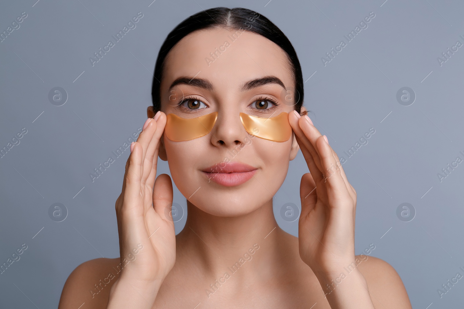 Photo of Beautiful young woman with under eye patches on grey background