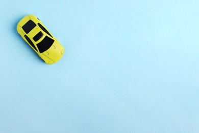 One yellow car on light blue background, top view with space for text. Children`s toy