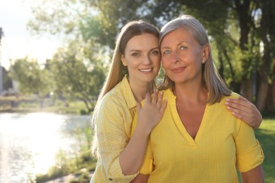 Photo of Family portrait of happy mother and daughter spending time together in park on sunny day. Space for text