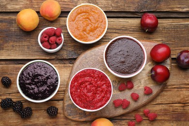 Photo of Different puree in bowls and fresh fruits on wooden table, flat lay