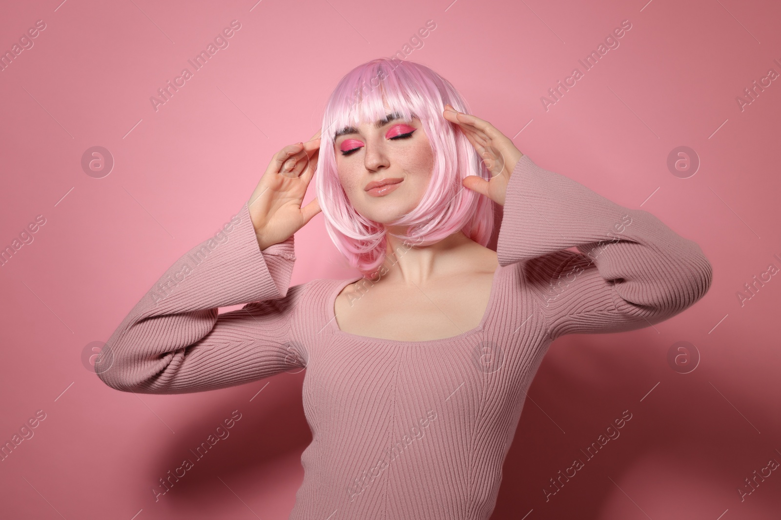 Photo of Beautiful woman with bright makeup and fake freckles on pink background