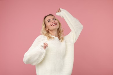 Photo of Happy woman in stylish warm sweater on pink background