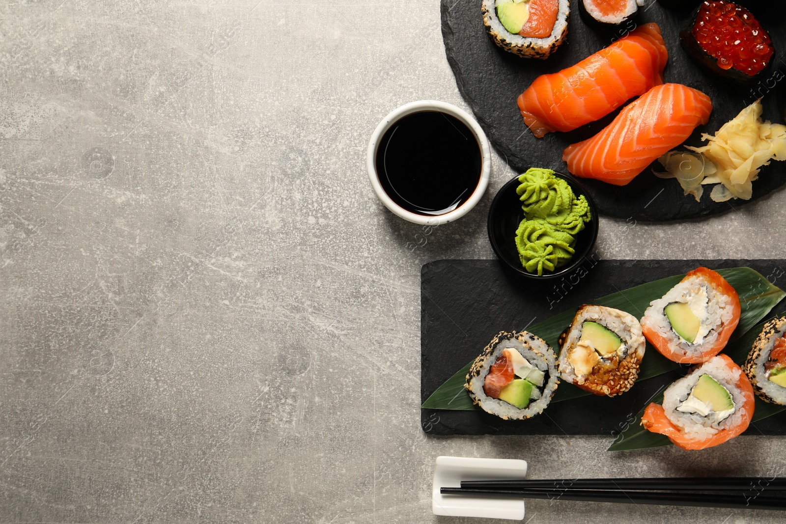 Photo of Different tasty sushi rolls on light grey table, flat lay. Space for text