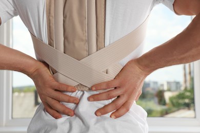 Photo of Closeup of man with orthopedic corset indoors, back view