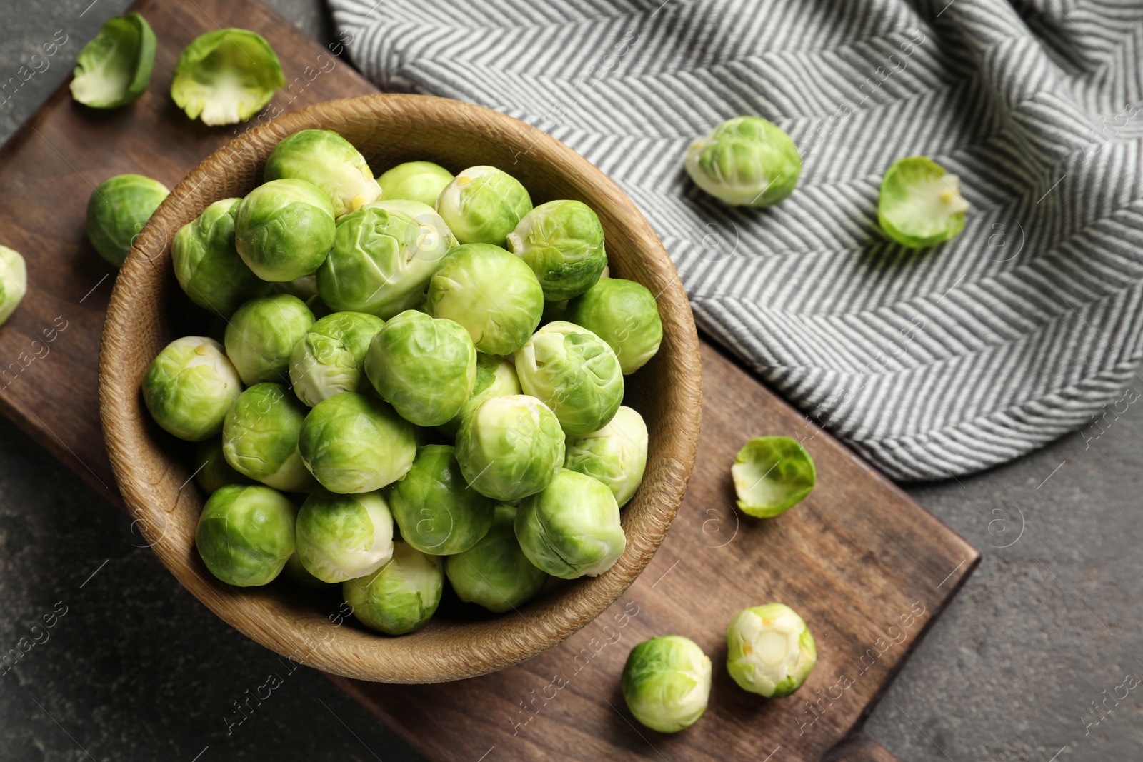 Photo of Board with bowl and Brussels sprouts on grey background, flat lay. Space for text