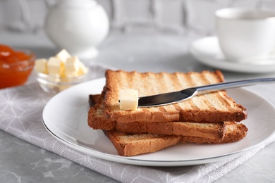 Photo of Tasty toasts with butter served for breakfast on grey marble table, closeup