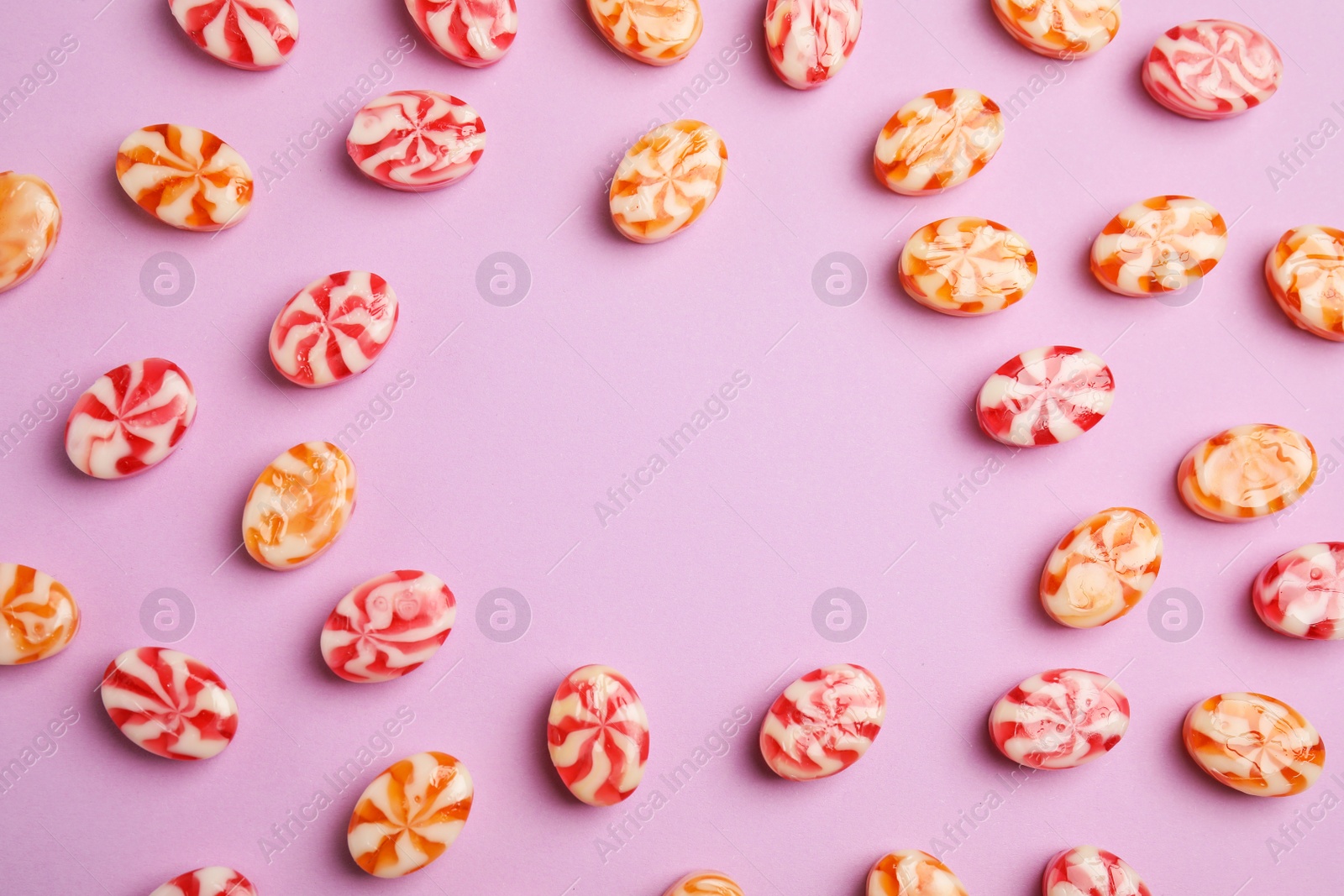 Photo of Flat lay composition with delicious colorful candies and space for text on color background