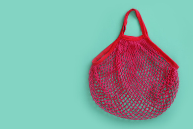 Photo of Empty net bag on turquoise background, top view. Space for text