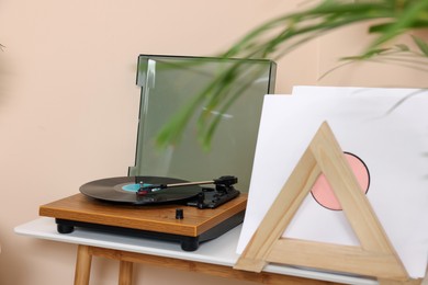 Photo of Stylish turntable with vinyl record on white table indoors
