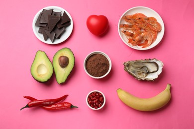 Photo of Natural aphrodisiac. Different food products and red decorative heart on pink background, flat lay