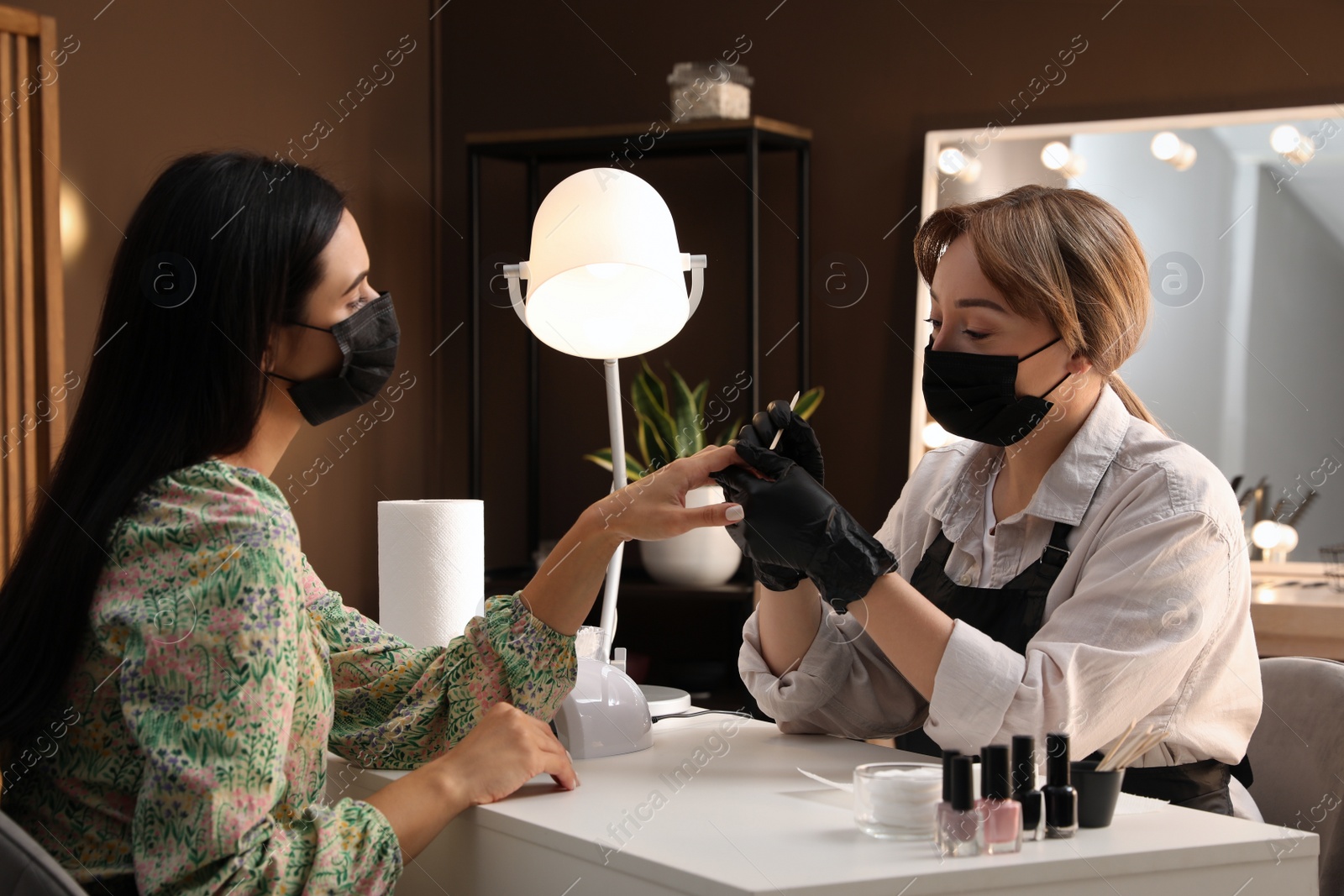 Photo of Professional manicurist working with client in salon. Beauty services during Coronavirus quarantine