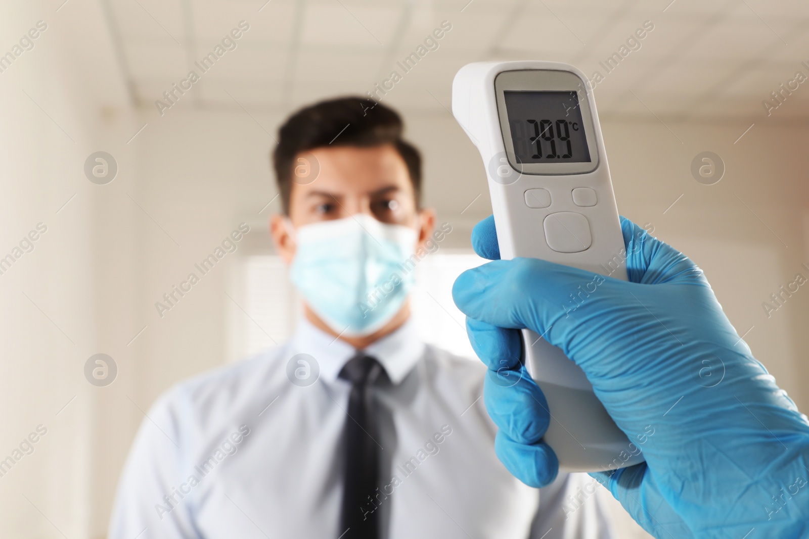 Photo of Doctor measuring man's temperature in office closeup. Prevent spreading of Covid-19