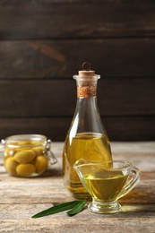 Photo of Beautiful composition with oil and ripe olives on wooden table