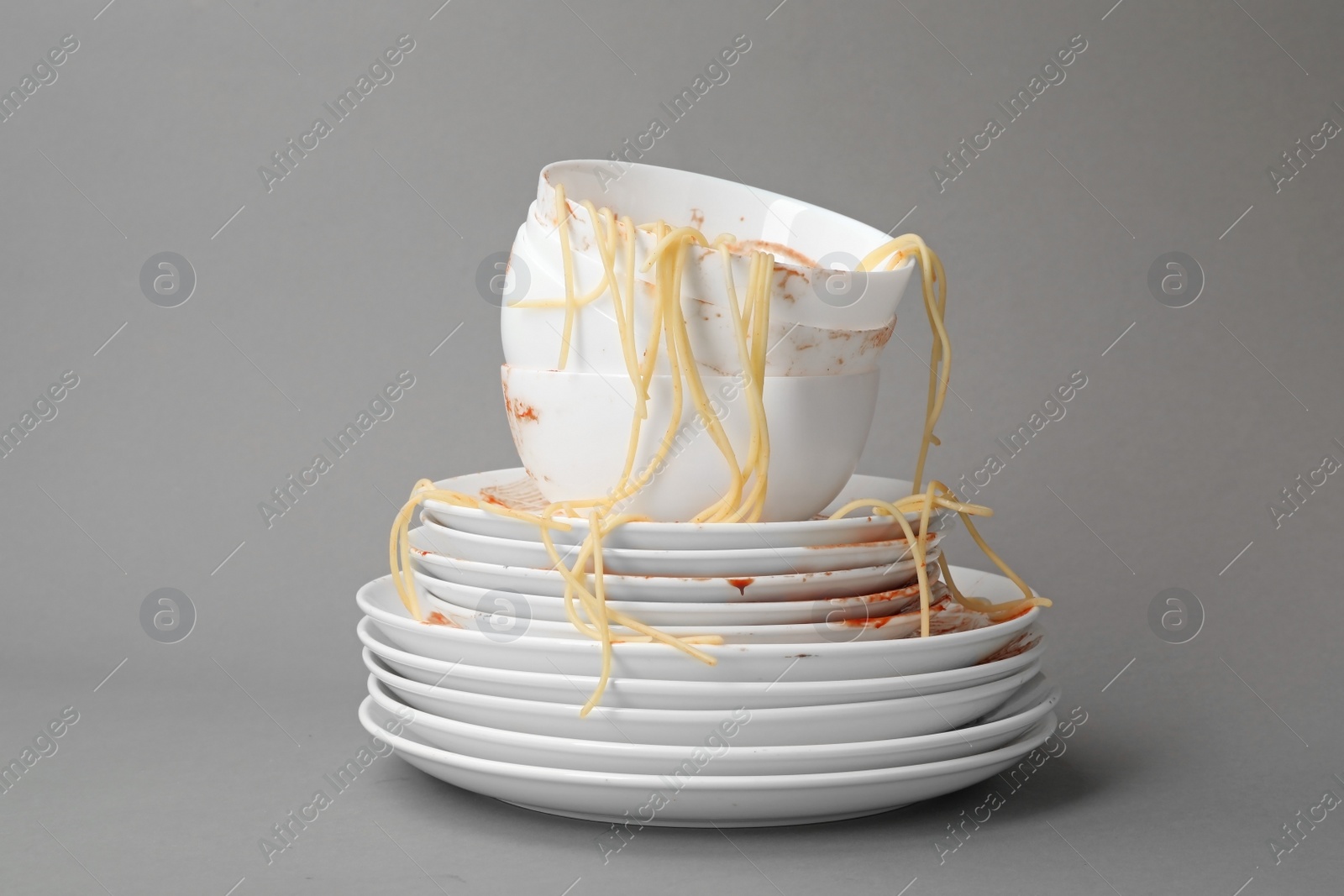 Photo of Set of dirty dishes with spaghetti leftovers on grey background