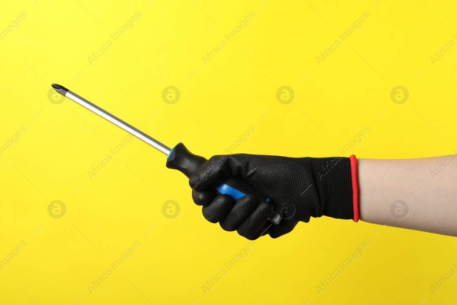 Photo of Woman holding screwdriver on yellow background, closeup