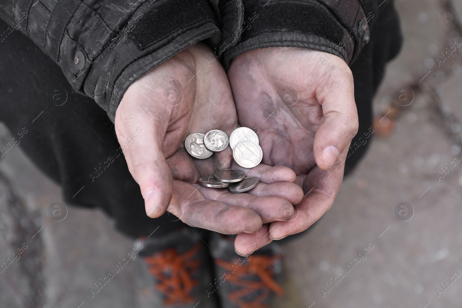 Photo of Poor homeless man holding coins outdoors, closeup