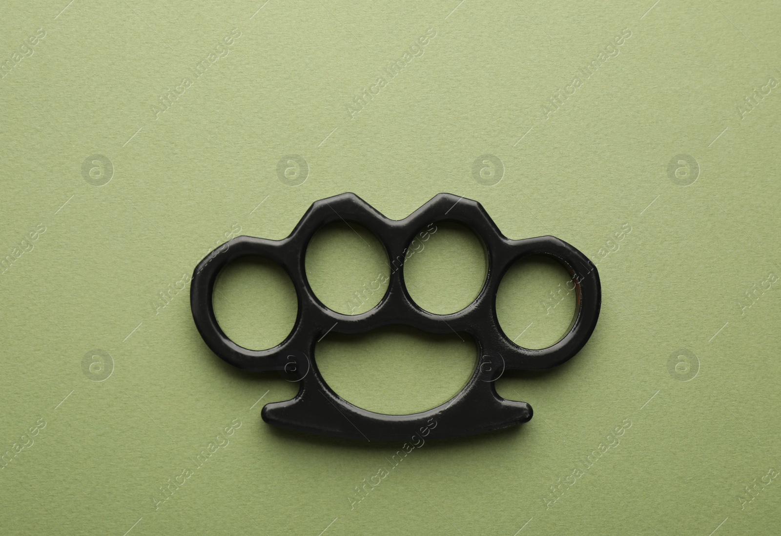 Photo of Black brass knuckles on green background, top view