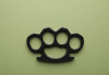 Black brass knuckles on green background, top view