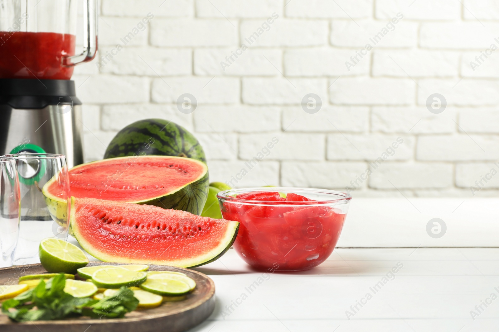 Photo of Fresh ingredients for making watermelon drink with lime on white table, space for text