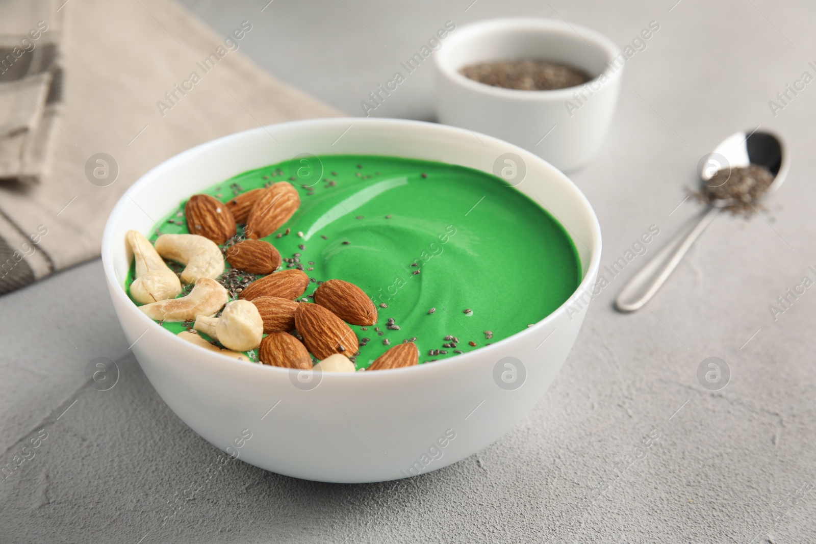 Photo of Bowl of spirulina smoothie with nuts and chia seeds on light table