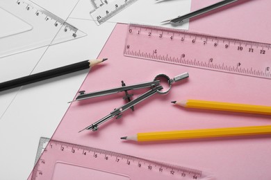 Different rulers, pencils and compass on pink background, above view