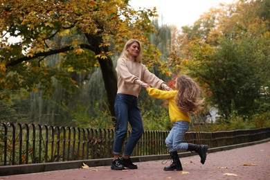 Photo of Mother having fun with her cute daughter in autumn park