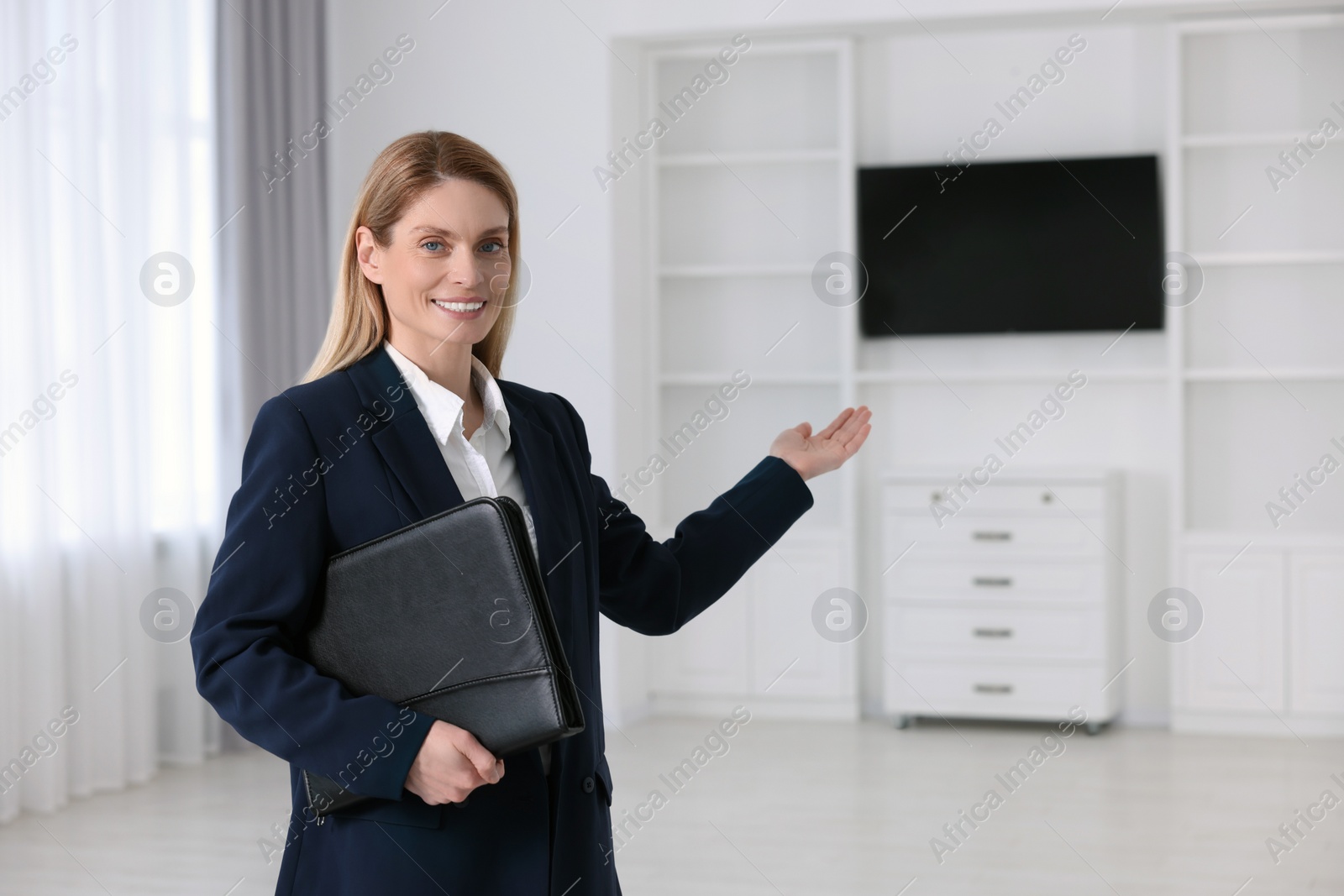 Photo of Happy real estate agent with leather portfolio showing new apartment. Space for text