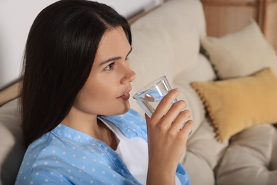 Photo of Young woman drinking water indoors. Refreshing drink