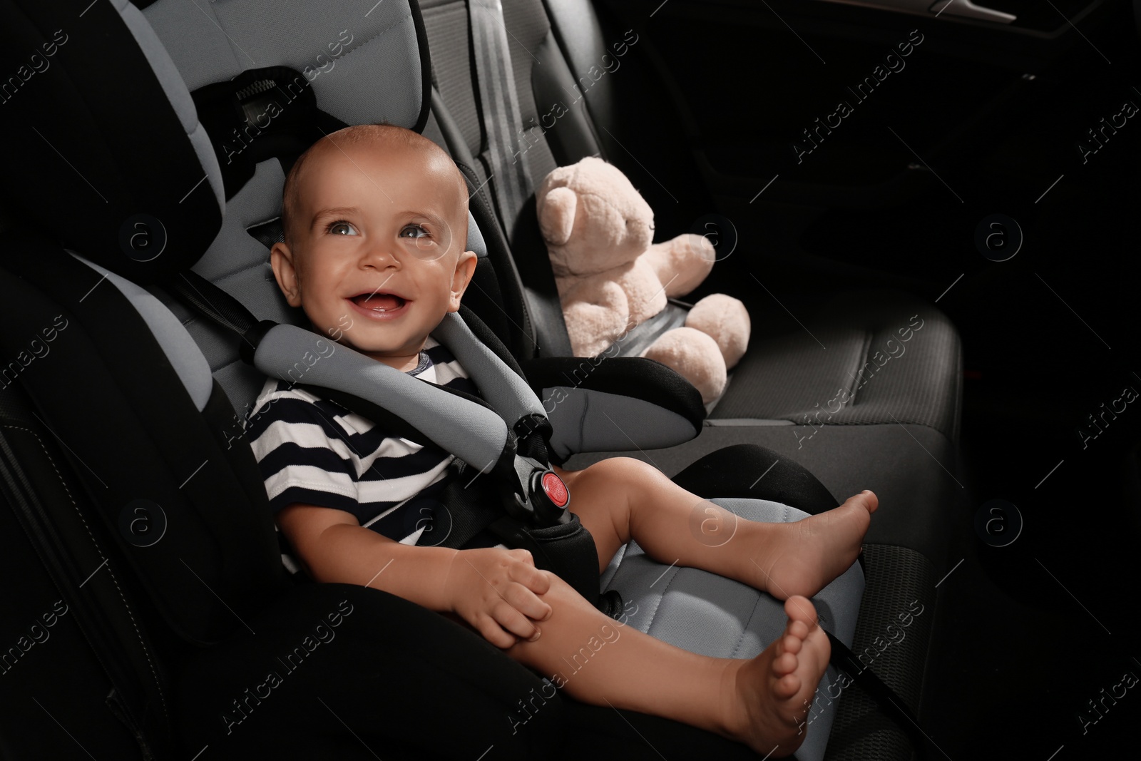 Photo of Cute little boy sitting in child safety seat inside car