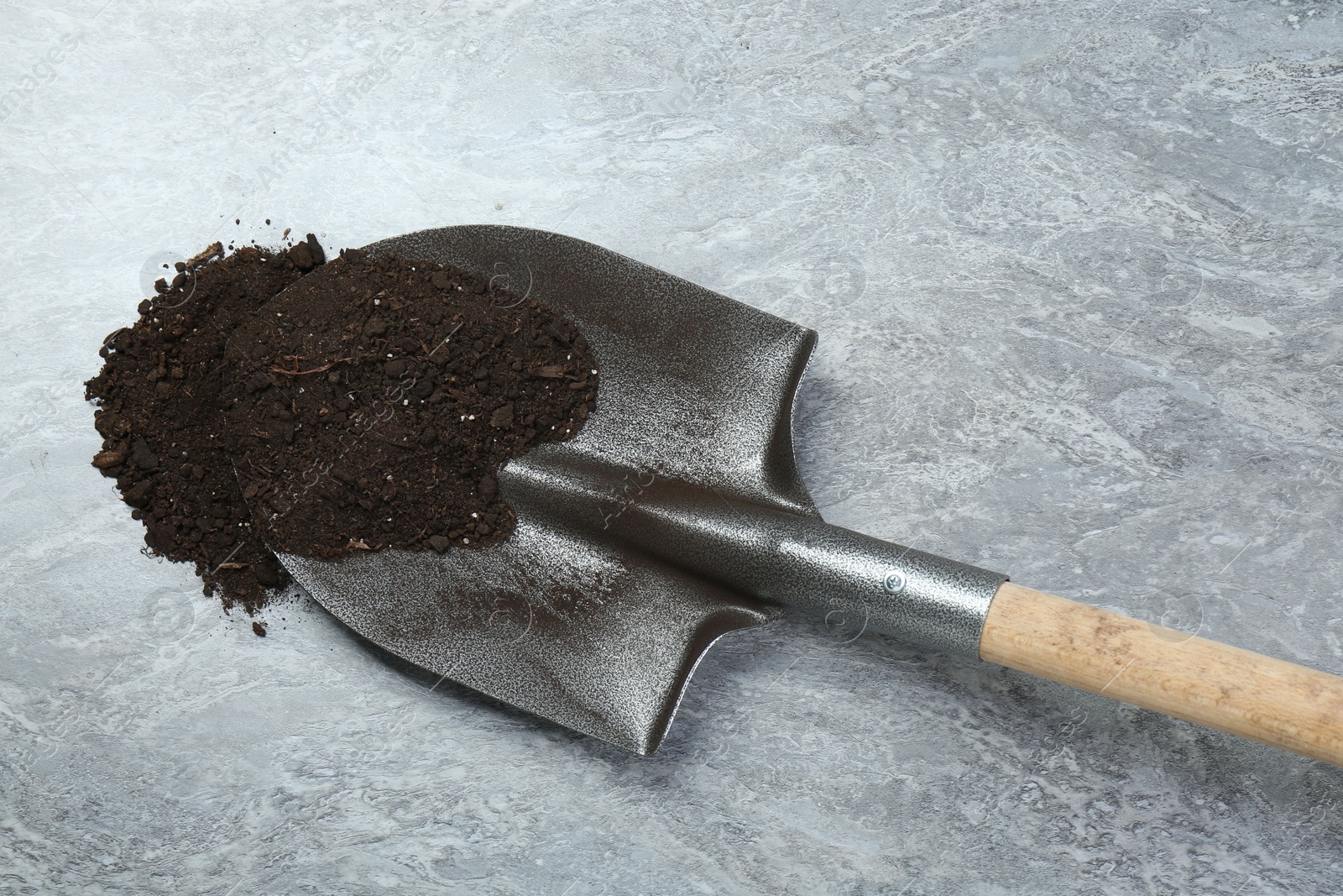 Metal shovel with fertile soil on gray textured surface, top view Photo of Metal shovel with fertile soil on gray textured surface, top view