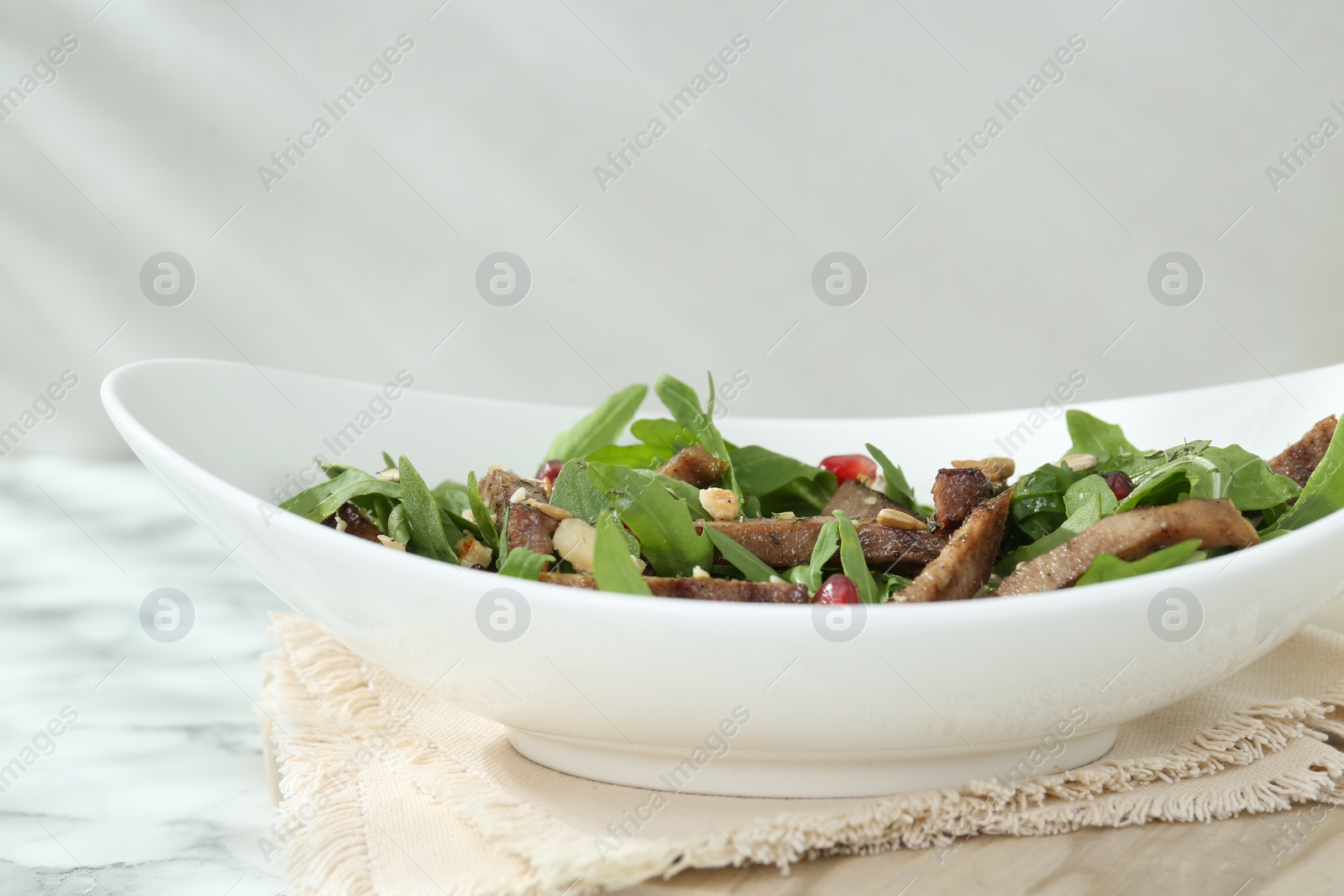 Photo of Delicious salad with beef tongue, arugula and seeds on white marble table, closeup