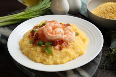 Plate with fresh tasty shrimps, bacon, grits and green onion on dark wooden table