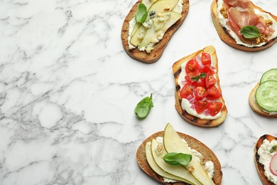 Photo of Different tasty bruschettas and space for text on marble background, flat lay