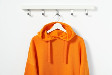 Hanger with orange hoodie on white wall