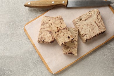 Photo of Tasty chocolate halva and knife on grey table, top view. Space for text